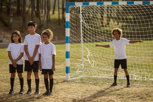 Foto fußballspielende kinder unter aufsicht eines fußballtrainers