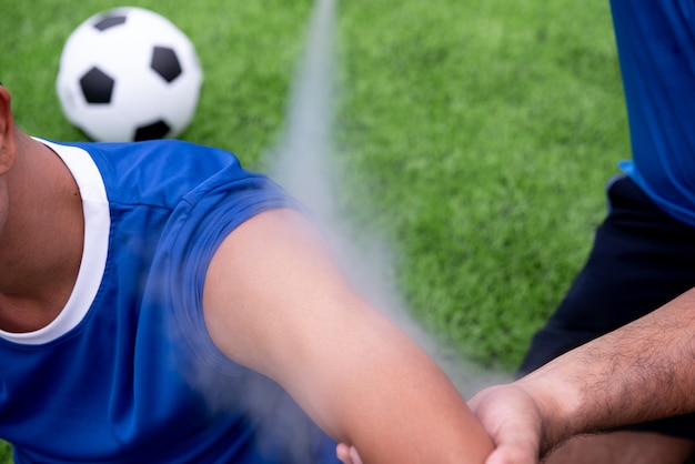 Foto fußballspieler, der ein blaues hemd, schwarze hosen trägt, verletzte im rasen während des rennens.