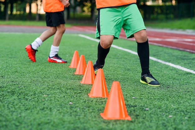 Fußballspieler, die zwischen orangefarbenen Plastikkegeln laufen