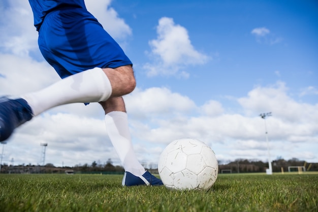 Fußballspieler im Blau ungefähr, zum des Balls zu treten