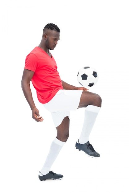 Fußballspieler in kontrollierendem Ball des roten Trikots