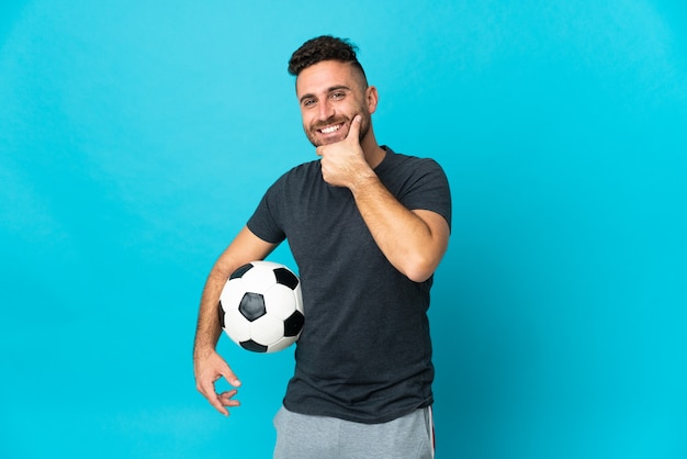 Fußballspieler isoliert auf blauem Hintergrund glücklich und lächelnd