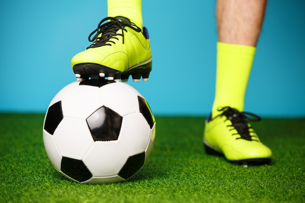 Fußballspieler mit Ball auf dem grünen Gras und dem blauen Hintergrund