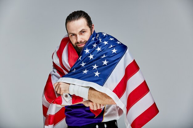 Fußballspieler mit Uniform und amerikanischer Flagge auf den Schultern stolz auf sein Land,