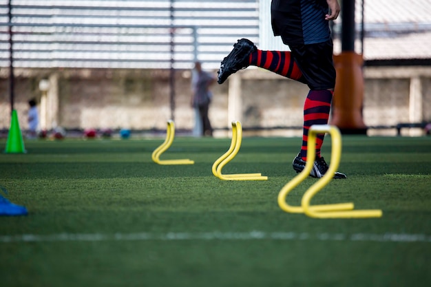 Fußballtaktiken auf Rasen mit Barriere zum Trainieren der Sprungfähigkeit von Kindern in der Fußballakademie