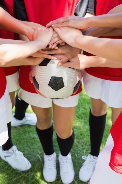 Fußballteam, das Hände auf Kugel stapelt