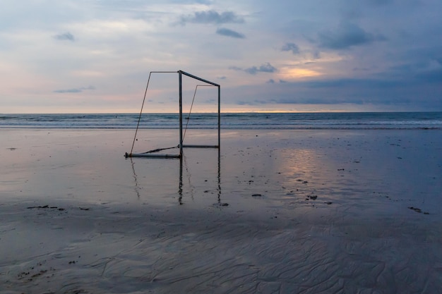 Fußballtor am Meeresstrand bei Sonnenuntergang