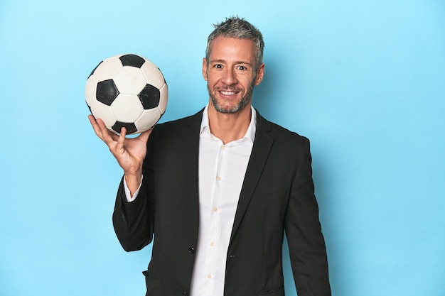 Fußballtrainer mit Fußball auf blauem Studiohintergrund