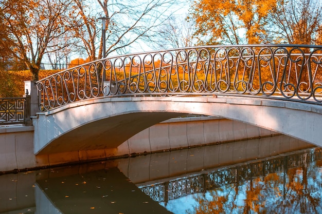 Fußgängerbrücke über den Fluss im Stadtpark Malerische Herbstlandschaft