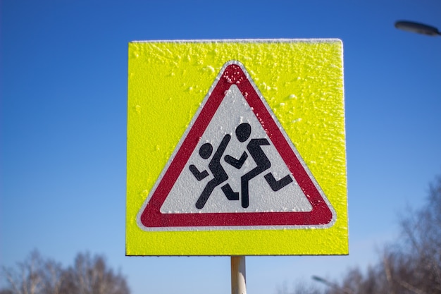 Fußgängerüberweg-Schild auf gelbem Grund. An einem sonnigen Wintertag.