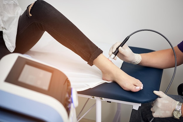 Fußlasertherapie Physiotherapeut Arzt verwendet medizinische Lasergeräte zur hochwirksamen Behandlung von Fußschmerzen Konzept der medizinisch-orthopädischen Behandlung und Rehabilitation