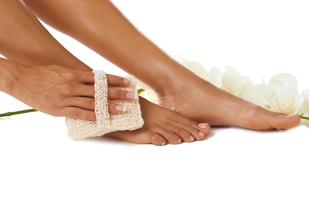 Fußpflege und Pediküre mit einer schwarzen Frau, die ihre Haut im Studio auf weißem Hintergrund reinigt, um ihre Haut zu peelen Spa-Blumen und Hand mit einer weiblichen Innenseite für die Epilation, Körperpflege oder Wellness