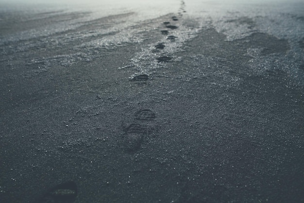 Fußspuren an einem schwarzen Sandstrand in Island