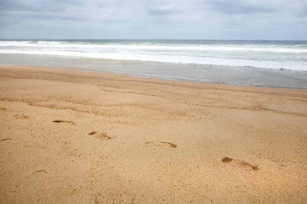 Fußspuren im Sand bei den Wellen des Strandes