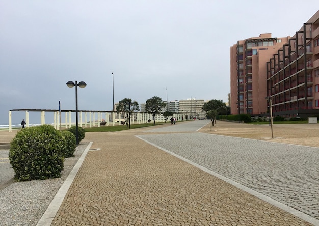 Foto fußweg inmitten von gebäuden gegen bewölkten himmel