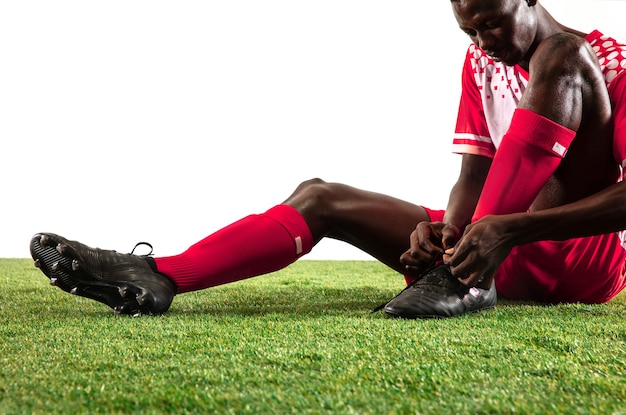 Fútbol americano africano profesional o jugador de fútbol del equipo rojo en movimiento aislado sobre fondo blanco de estudio. Colocar al hombre en acción, emoción, momento emocional. Concepto de movimiento en el juego.