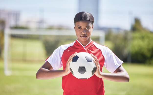 Fútbol y deportes con jugadora y atleta listos para un partido o competencia con pelota en un campo o estadio al aire libre Retrato de una mujer negra seria lista para entrenar