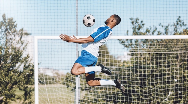 El fútbol deportivo y el hombre saltan con el juego de pelota, entrenan y hacen ejercicio en el campo al aire libre. Entrenamiento físico y jugador de fútbol masculino para portero de defensa y en acción por goles en competencia.