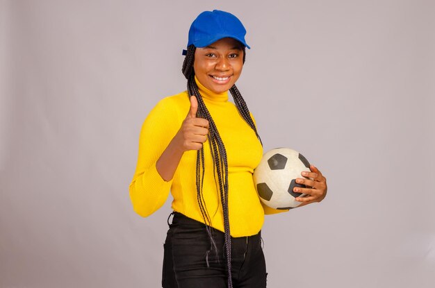 Fútbol joven sosteniendo la pelota e hizo los pulgares hacia arriba