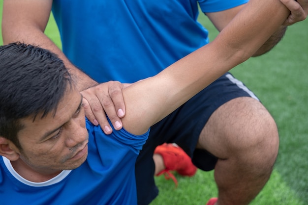 Futbolista con una camisa azul, pantalones negros heridos en el césped durante la carrera.