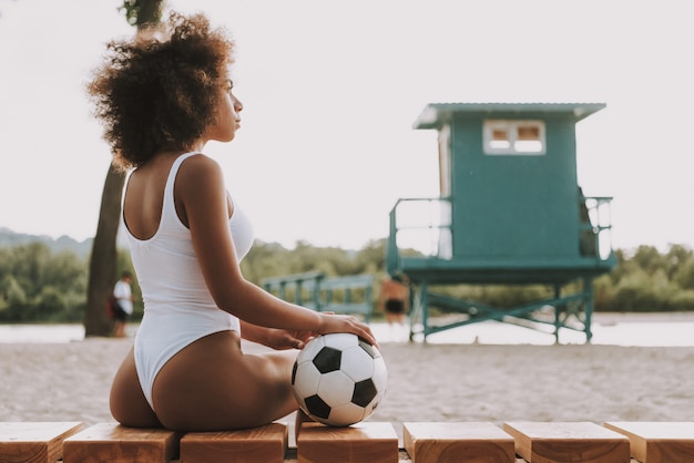 Futbolista femenina mirando la puesta de sol en el mar