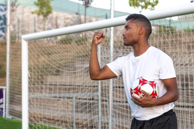 Futbolista latino con balón en mano celebrando un gol Concepto de jugador celebrando un gol con balón en mano