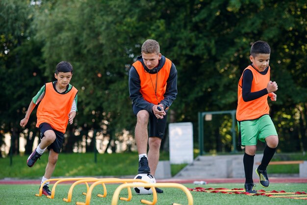 Los futbolistas activos entrenan juntos en el campo de fútbol y siguen las instrucciones de un entrenador profesional.