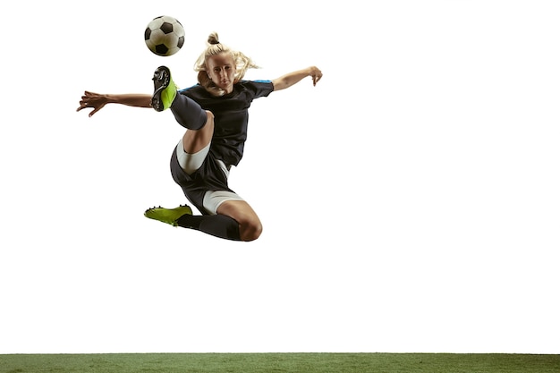 Futebol feminino jovem ou jogador de futebol com cabelo comprido em roupas esportivas e botas chutando a bola para o gol no salto sobre fundo branco. Conceito de estilo de vida saudável, esporte profissional, movimento, movimento.