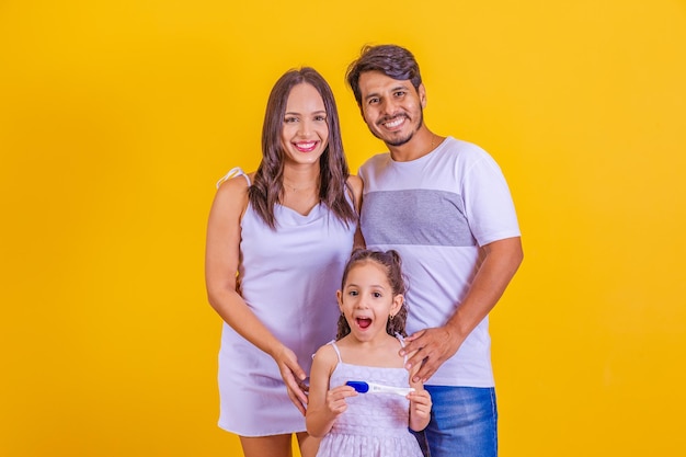 Foto futura hermana mayor con una prueba de embarazo positiva con su familia en crecimiento feliz madre padre e hija con prueba de embarazo positiva