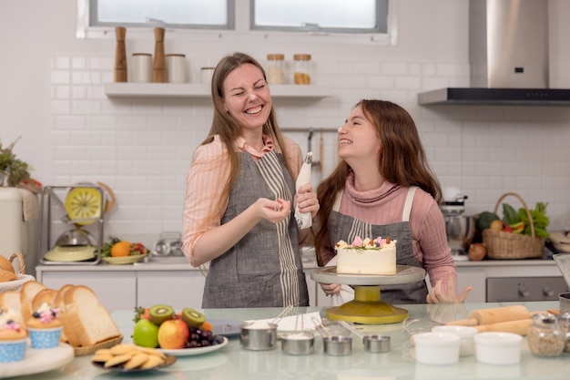 Futura madre e hija decorar cupcakes en una mesa de la cocina, pasar un buen rato juntos mientras comen pasteles recién horneados