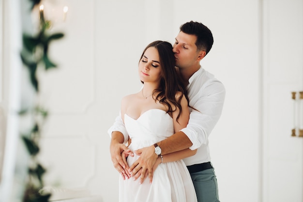 Futura madre y padre abrazándose y posando