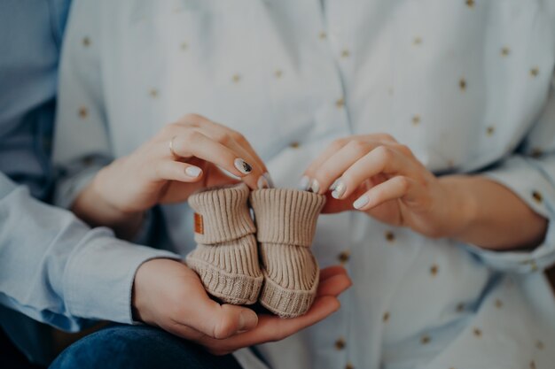 Futura mulher e homem prontos para se tornarem pais seguram sapatos infantis