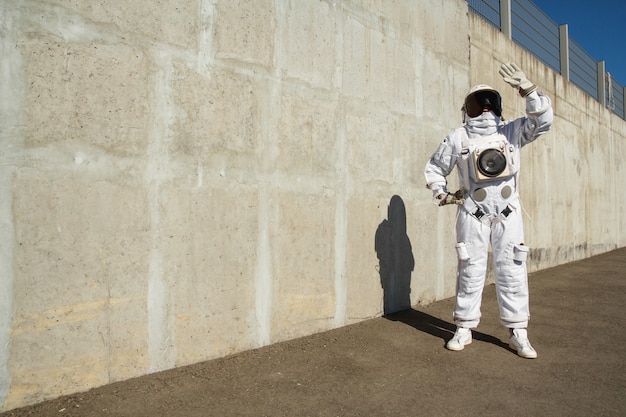 Futuristischer Astronaut in einem Helm gegen graue Wände. Fantastisches kosmisches Kostüm.