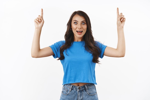 Foto futuro brilhante para estudantes como você visita o perfil mulher sorridente feliz animada se pergunta que ela encontrou exatamente o que precisa apontar os dedos para cima contando ótimas notícias em pé fundo branco otimista