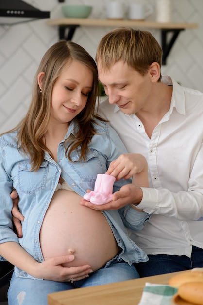 Futuro padre con su esposa embarazada sosteniendo calcetines de bebé junto a su