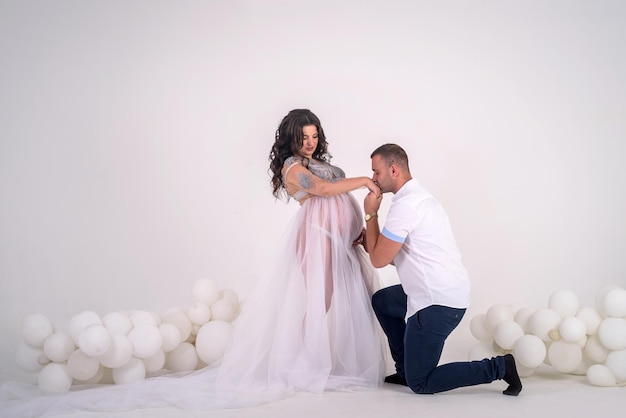 Futuro pai beijando as mãos da esposa grávida. Lindo casal em estúdio