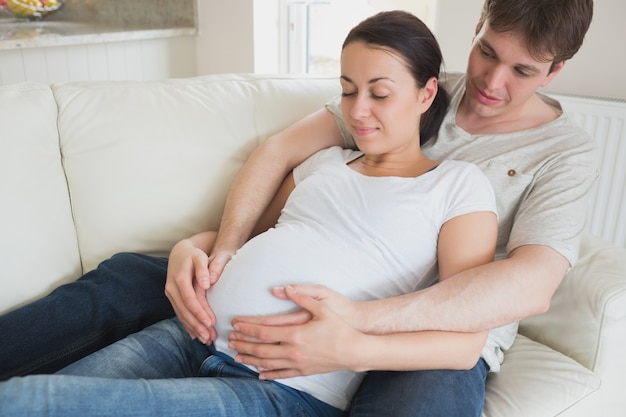 Foto futuros padres se relajan en el sofá