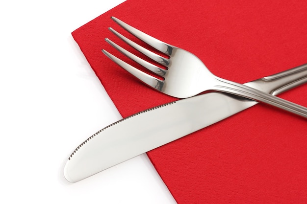 Gabel und Messer in einem roten Tuch getrennt auf Weiß