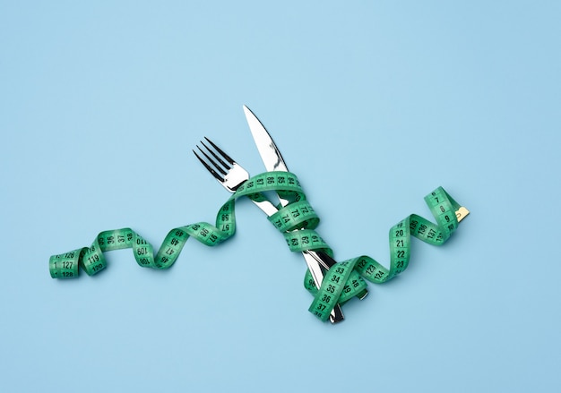 Gabel und Messer in grünes Maßband gewickelt