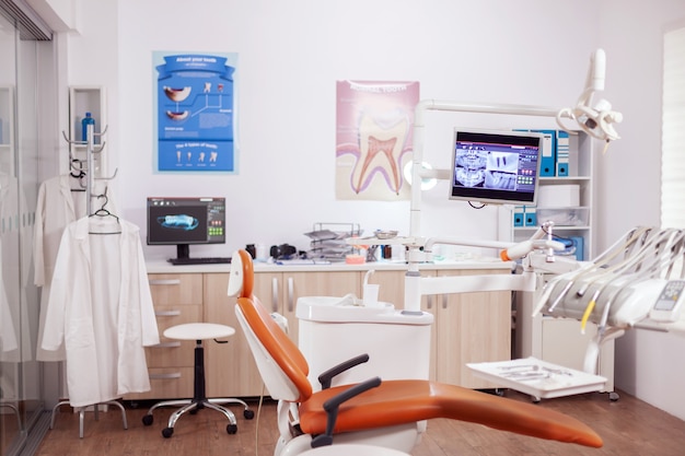 Gabinete de dentista naranja moderno con utensilios estériles. Armario de estomatología sin nadie dentro y equipo naranja para tratamiento bucal.