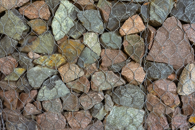 Gabion, Textur, Hintergrund. Wand aus natürlichen Steinen und Metallzäunen. Landschaftsbau. Fechten und Terrassen