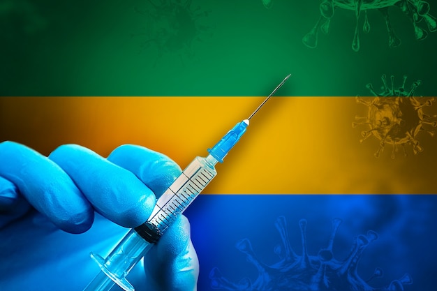 Gabun Covid19-Impfkampagne Hand in einem blauen Gummihandschuh hält Spritze vor Flagge