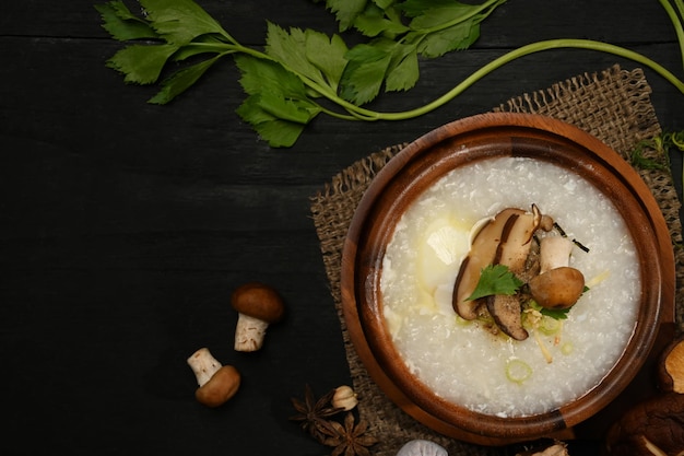 Gachas de arroz con champiñones shiitake de huevo hervido y cebolleta en un tazón de madera sobre una mesa servida