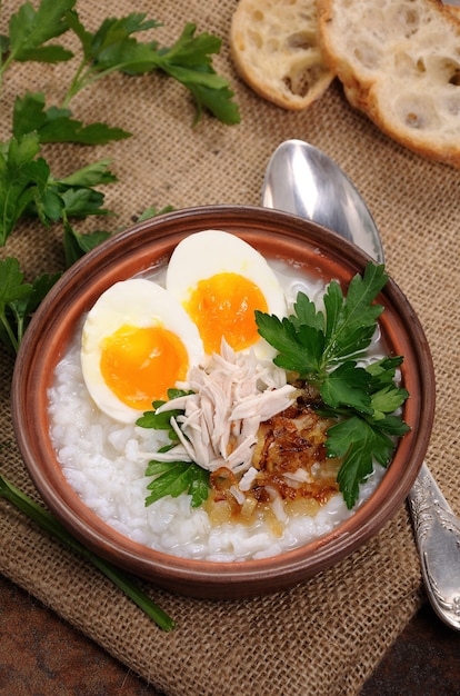 Gachas de arroz con jengibre congee con huevo, pollo, chalotas crujientes y perejil