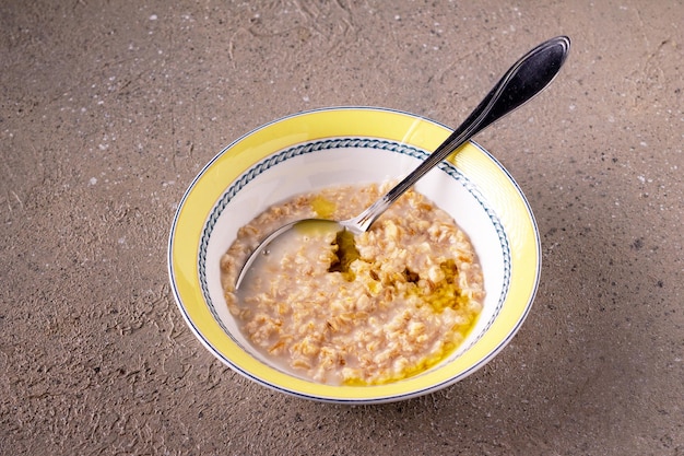 Foto gachas de avena con aceite de oliva en un plato redondo de cerámica sobre una mesa beige