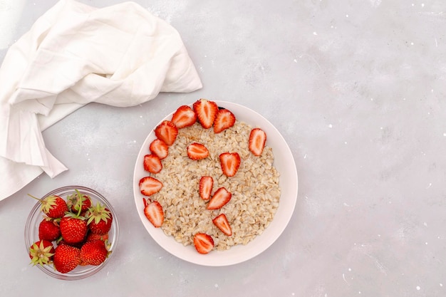 Gachas de avena con bayas de fresas de verano Gachas de avena en un tazón Comida saludable desayuno estilo de vida dieta nutrición adecuada Vista superior plana sobre fondo de mesa gris espacio de copia