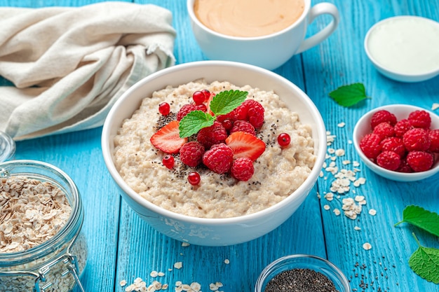 Gachas de avena con bayas frescas y semillas de chía sobre un fondo azul.