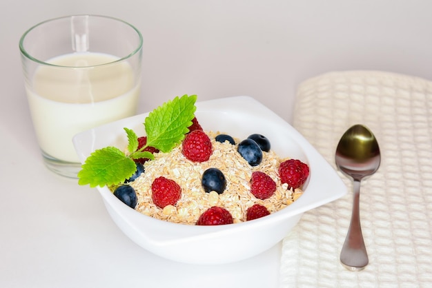 Gachas de avena con bayas en un recipiente aislado en blanco