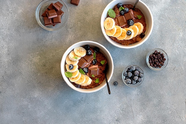 Gachas de avena con chocolate con arándanos, hojas de menta y plátano en un tazón. concepto de desayuno