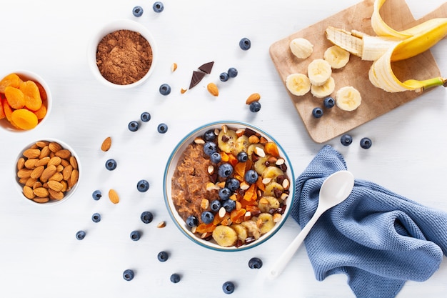 Gachas de avena y chocolate con arándanos, nueces, plátano, albaricoque seco para un desayuno saludable. Vista superior